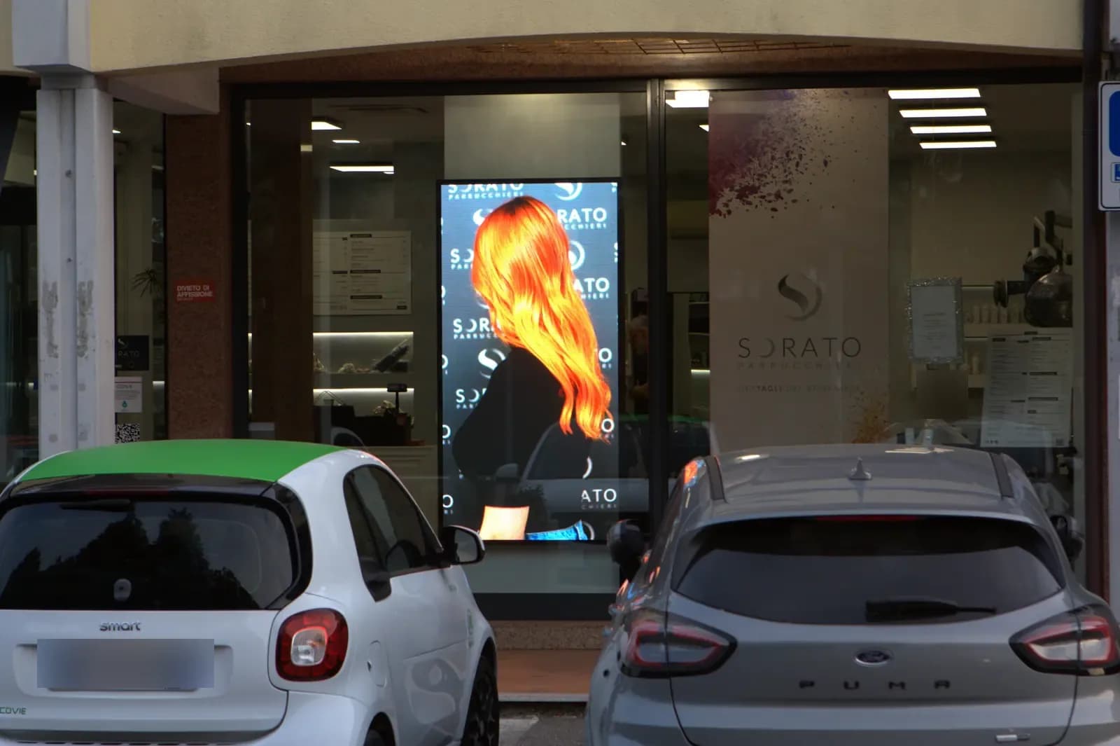 Ledwall in vetrina da Sorato Parrucchieri con immagine di un taglio
